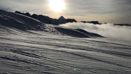 Pictures & Impressions • Der Grubacher: Hotel in Gerlos Winter landscape with sun over a snow-covered slope and a sea of fog in front of mountain silhouettes