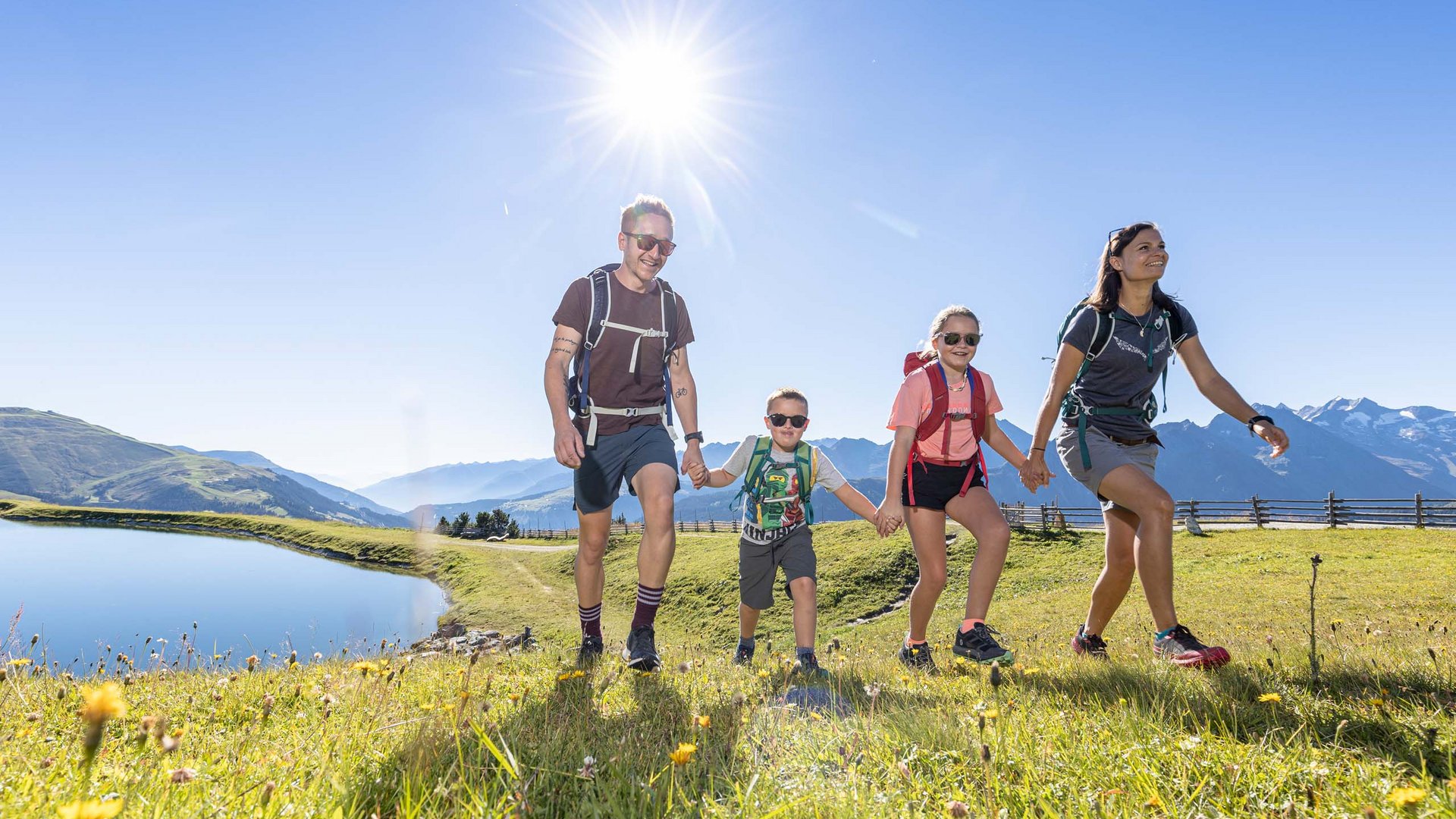 Familie beim Wandern auf einer Wiese mit Bergsee