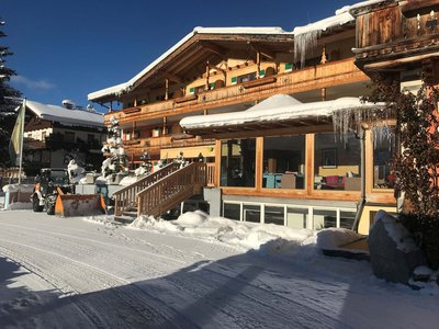 Biohotel in Tirol • Der Grubacher: Hotel in Gerlos Grubachhof im Winter mit gläsernem Restaurantbereich und verschneiter Umgebung