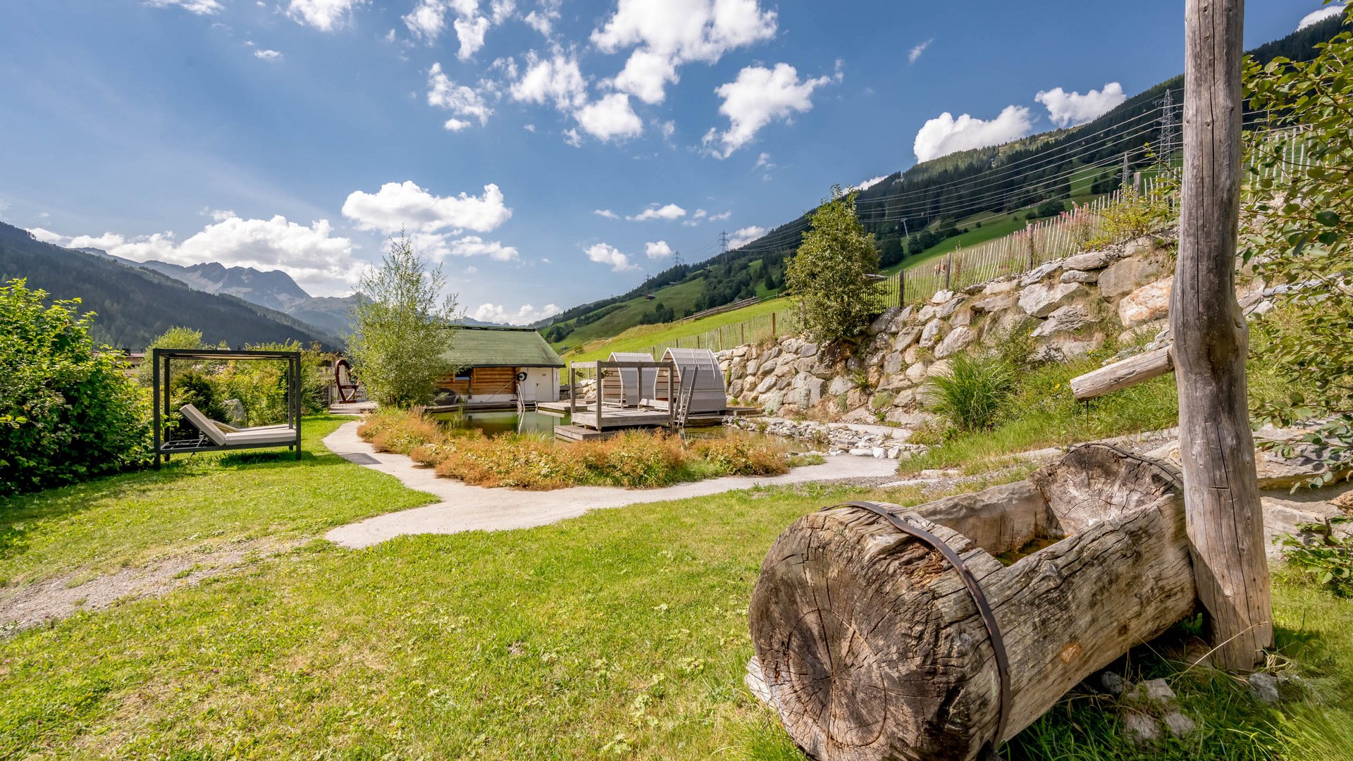 Our history • Der Grubacher: Eco Hotel in Gerlos Fountain in the garden with lounging area and natural swimming pond in summer