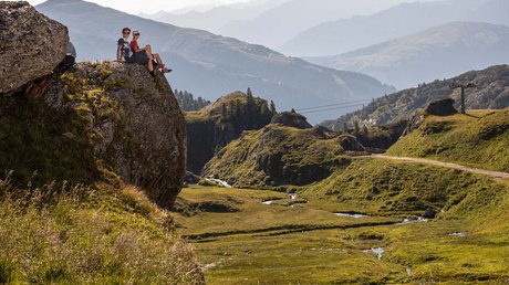Pictures & Impressions • Der Grubacher: Hotel in Gerlos Couple sitting on a large rock overlooking meadows, streams, and mountains