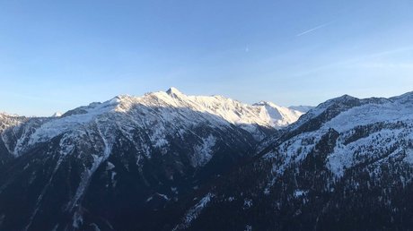 Pictures & Impressions • Der Grubacher: Hotel in Gerlos Panoramic view of a snowy mountain landscape with dark forests and white peaks