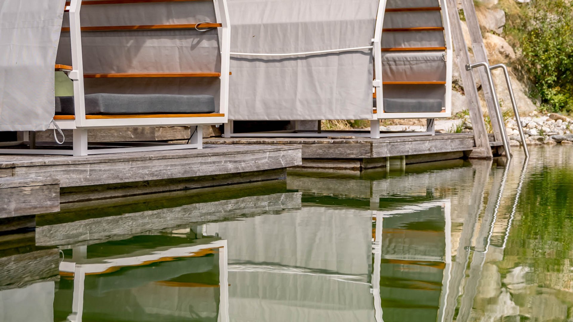 Wasserwelt in Gerlos • Der Grubacher: Biohotel in Tirol Gartenliege mit Spiegelung im Schwimmteich