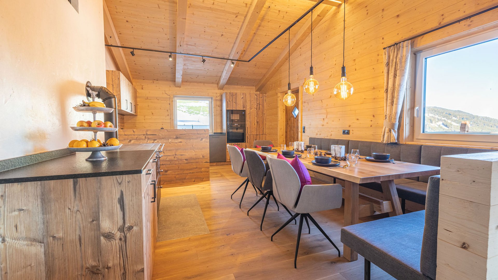 Grubi's Freizeitwohnsitz • Der Grubacher Offene Küche und Essbereich mit Holzmöbeln, moderner Ausstattung und Blick nach draußen