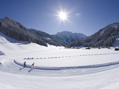 Erlebnisse im Zillertal • Der Grubacher: Biohotel in Gerlos Zwei Langläufer gleiten durch verschneite Winterlandschaft bei Sonnenschein