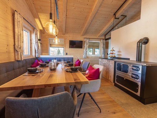 Grubi's Freizeitwohnsitz • Der Grubacher Großer Holztisch im Essbereich, dekoriert mit Tellern, Gläsern, Kissen und stimmungsvoller Beleuchtung