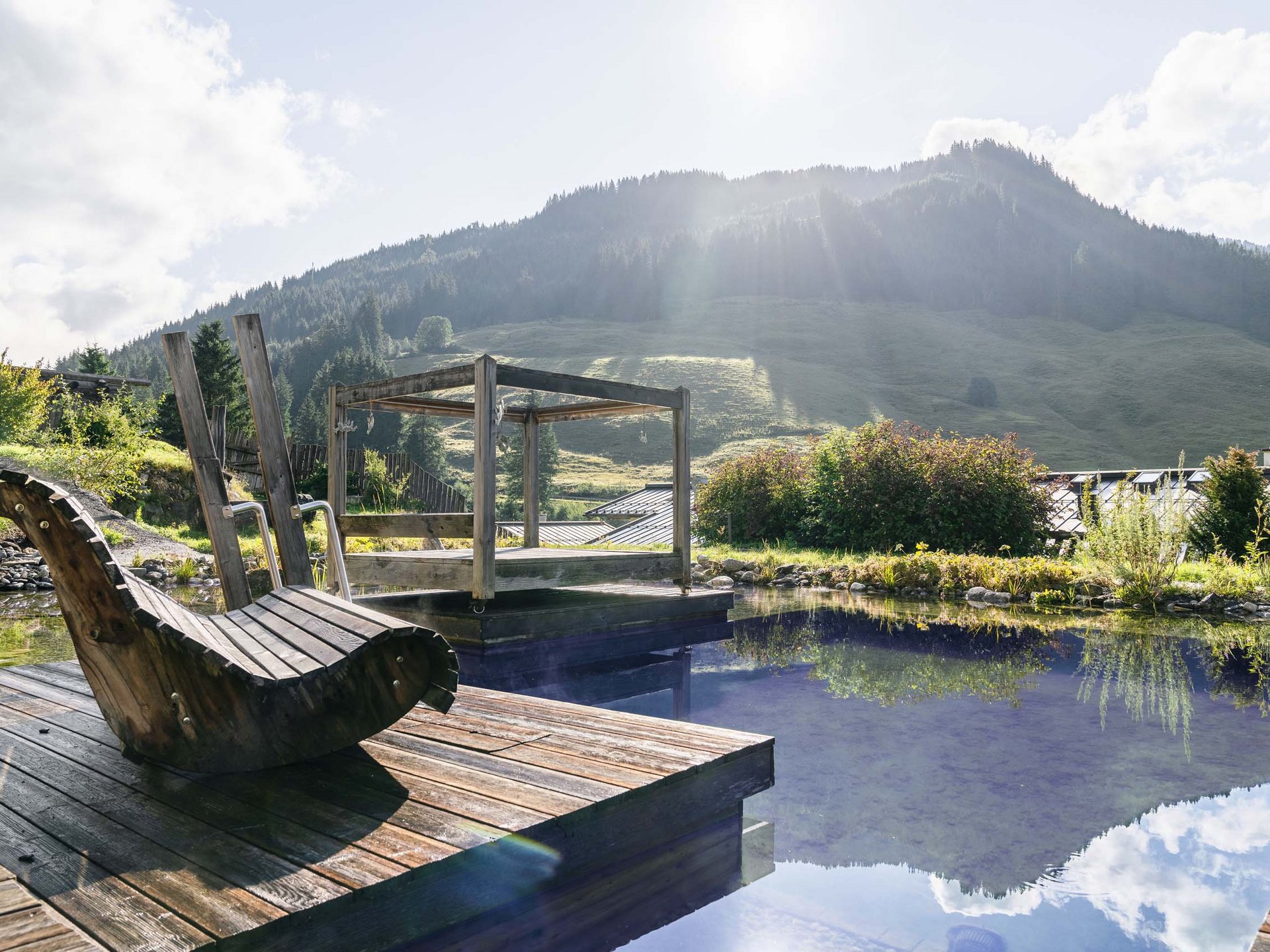 Naturbadeteich mit Holzliege und Plattform im Wasser