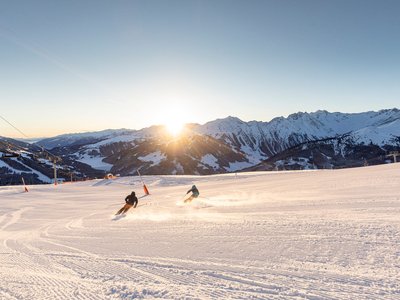 Der Grubacher • The best choice among the eco hotels in Tyrol Skiers enjoy turns on an empty slope at sunset