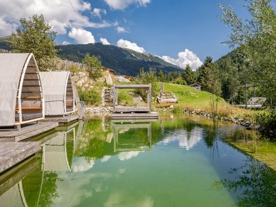 Eco Hotel in Tyrol • Der Grubacher: Eco Hotel in Gerlos Swimming pond in the garden with sun lounger and view of the mountains