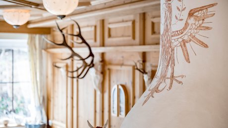 Pictures & Impressions • Der Grubacher: Hotel in Gerlos Tiled stove in a wood-paneled room with animal trophies