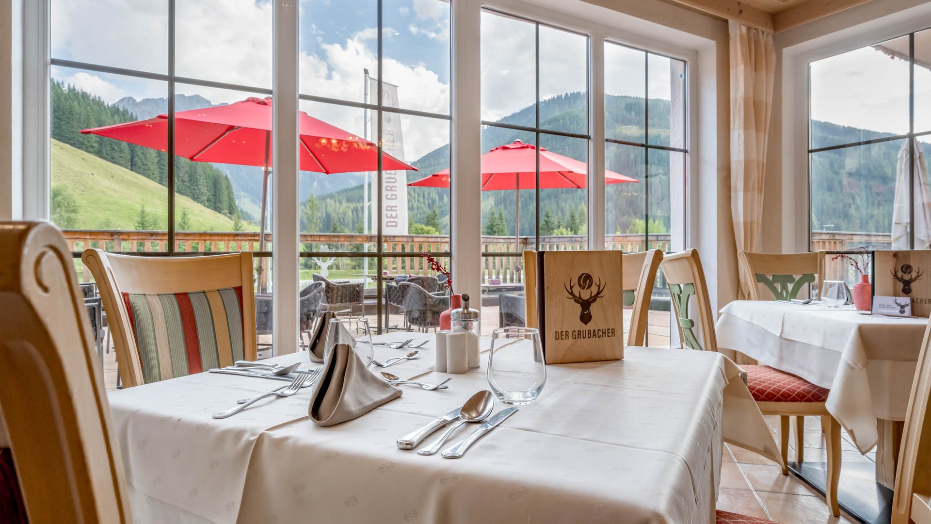 Delicacies in Gerlos • Der Grubacher: Eco Hotel in Tyrol Set tables in the restaurant with a view of the landscape