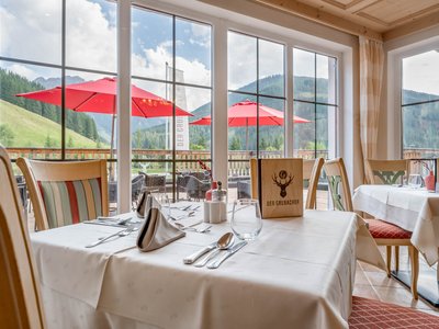Der Grubacher • Biohotels in Gerlos im Zillertal in Tirol Gedeckte Tische im Restaurant mit Blick auf die Landschaft