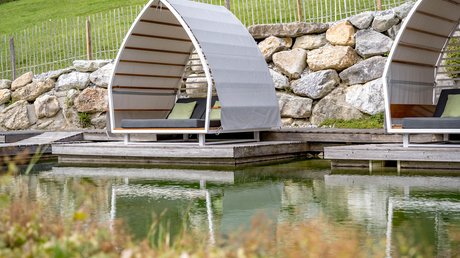 Pictures & Impressions • Der Grubacher: Hotel in Gerlos Garden loungers by the swimming pond with a view of the meadow